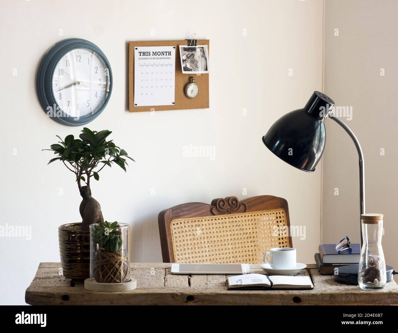 Un tranquillo ufficio domestico decorato con elementi naturali sostenibili di decor (come piante, rattan, canna, sughero e iuta) e una scrivania di legno rigenerata Foto Stock