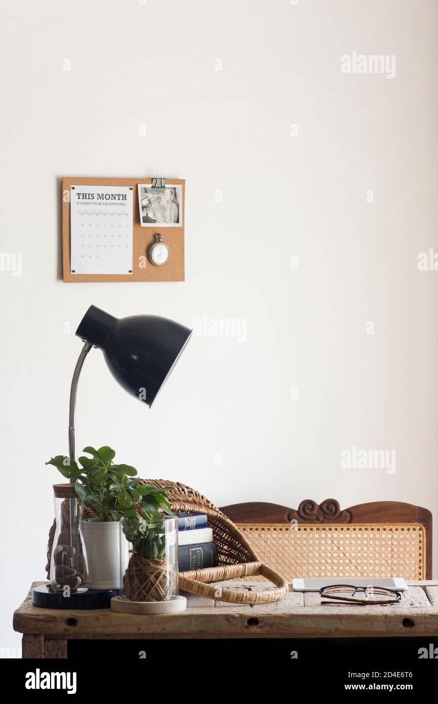 Un tranquillo ufficio domestico decorato con elementi naturali sostenibili di decor (come piante, rattan, canna, sughero e iuta) e una scrivania di legno rigenerata Foto Stock