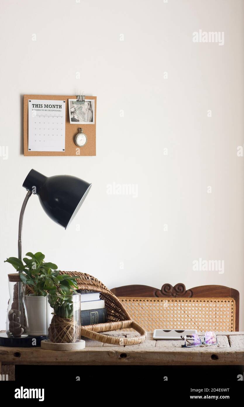 Un tranquillo ufficio domestico decorato con elementi naturali sostenibili di decor (come piante, rattan, canna, sughero e iuta) e una scrivania di legno rigenerata Foto Stock