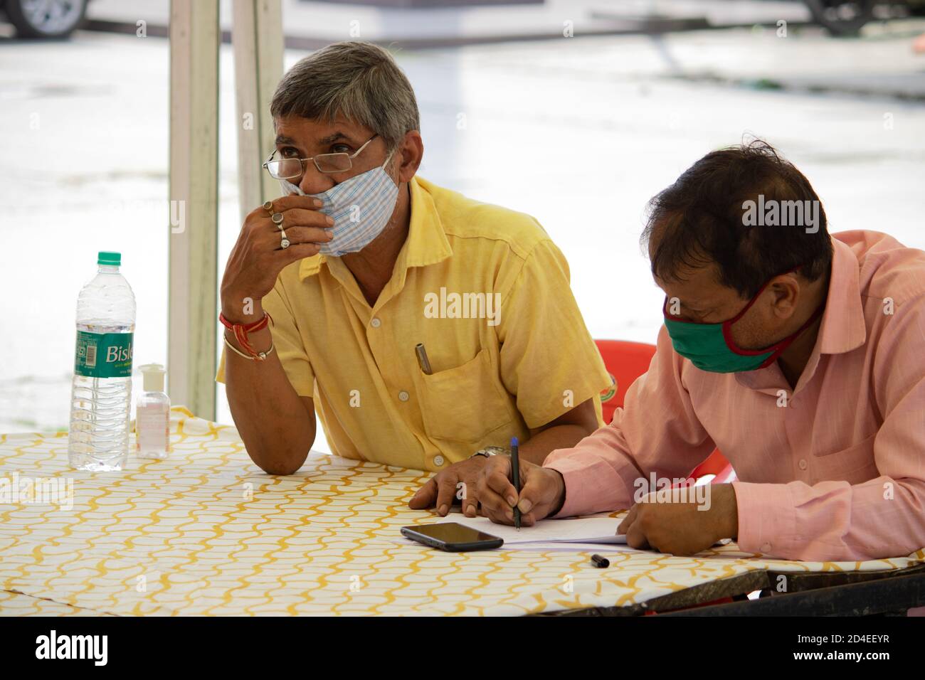 Dehradun, Uttarakhand/India-Settembre 12 2020:funzionari governativi che indossano la maschera facciale che effettuano la registrazione dei passeggeri alla stazione ferroviaria. Foto Stock