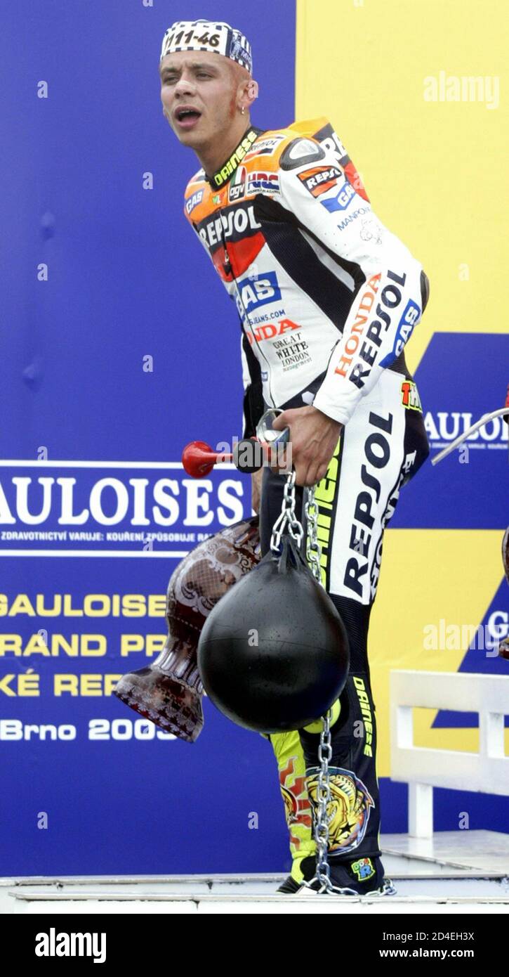 Valentino Rossi d'Italia, vestito in un cappellino prigioniero, con una  palla e una catena (in primo piano) e il trofeo dei vincitori (oscurato),  esce dal podio dopo aver festeggiato la sua vittoria