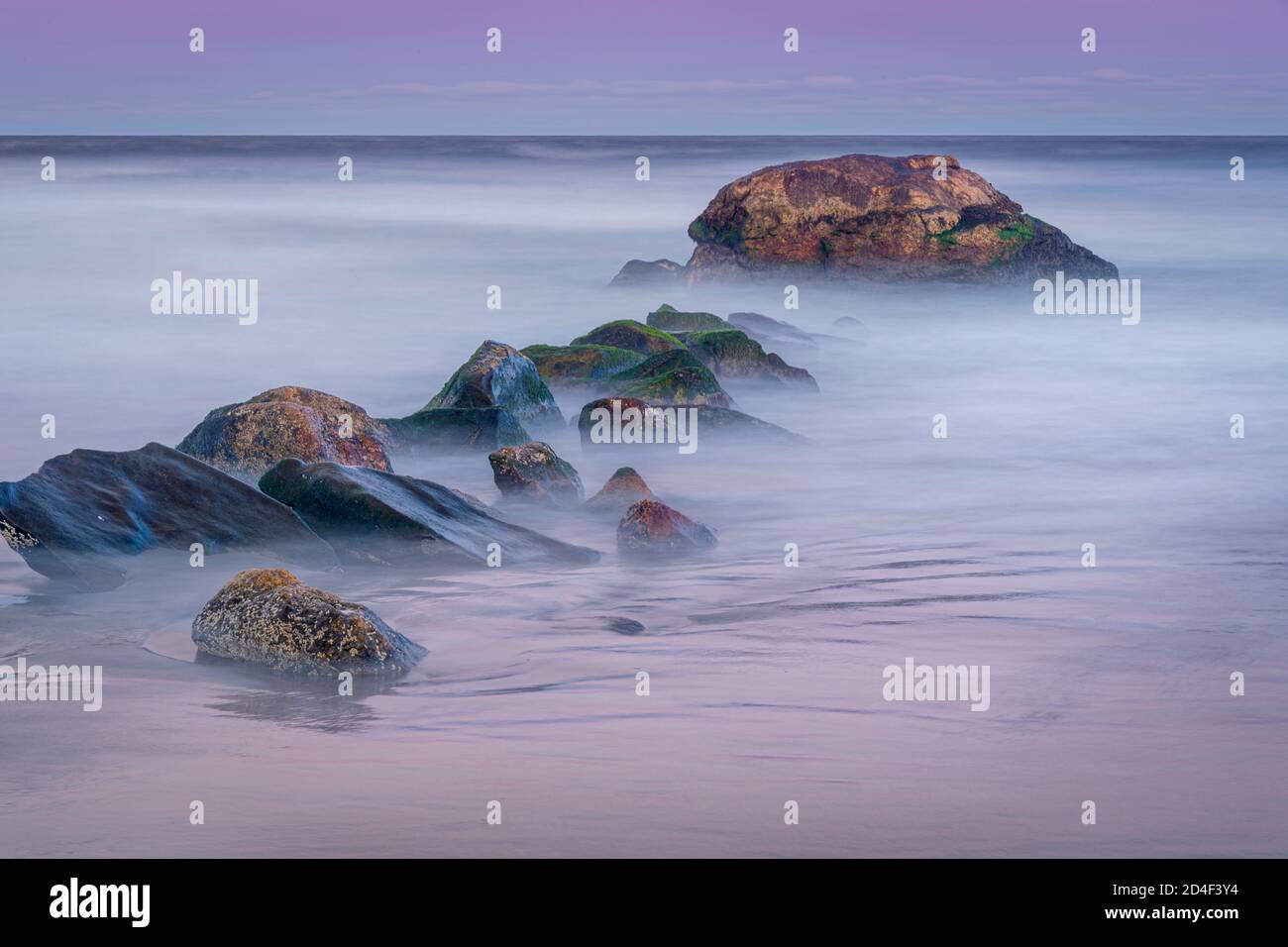 Misty onde sfocate e surf con rocce all'alba, Narragansett, Rhode Island USA Foto Stock