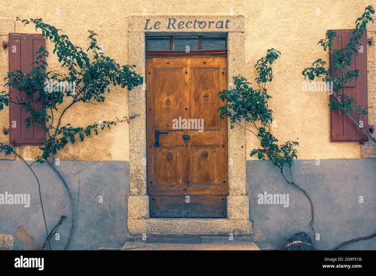 Vintage con piante intrecciate facciata con porta vecchia. La cornice della porta è coperta dal testo francese "le rectorat", che significa ricettorato. Foto Stock