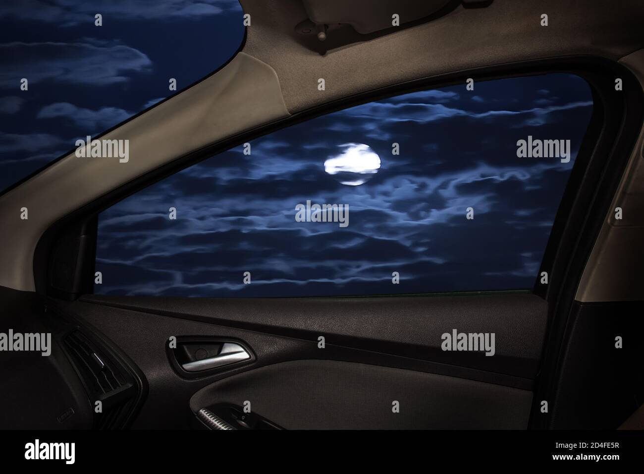 notte illuminata di luna dietro il finestrino laterale di un'auto Foto Stock