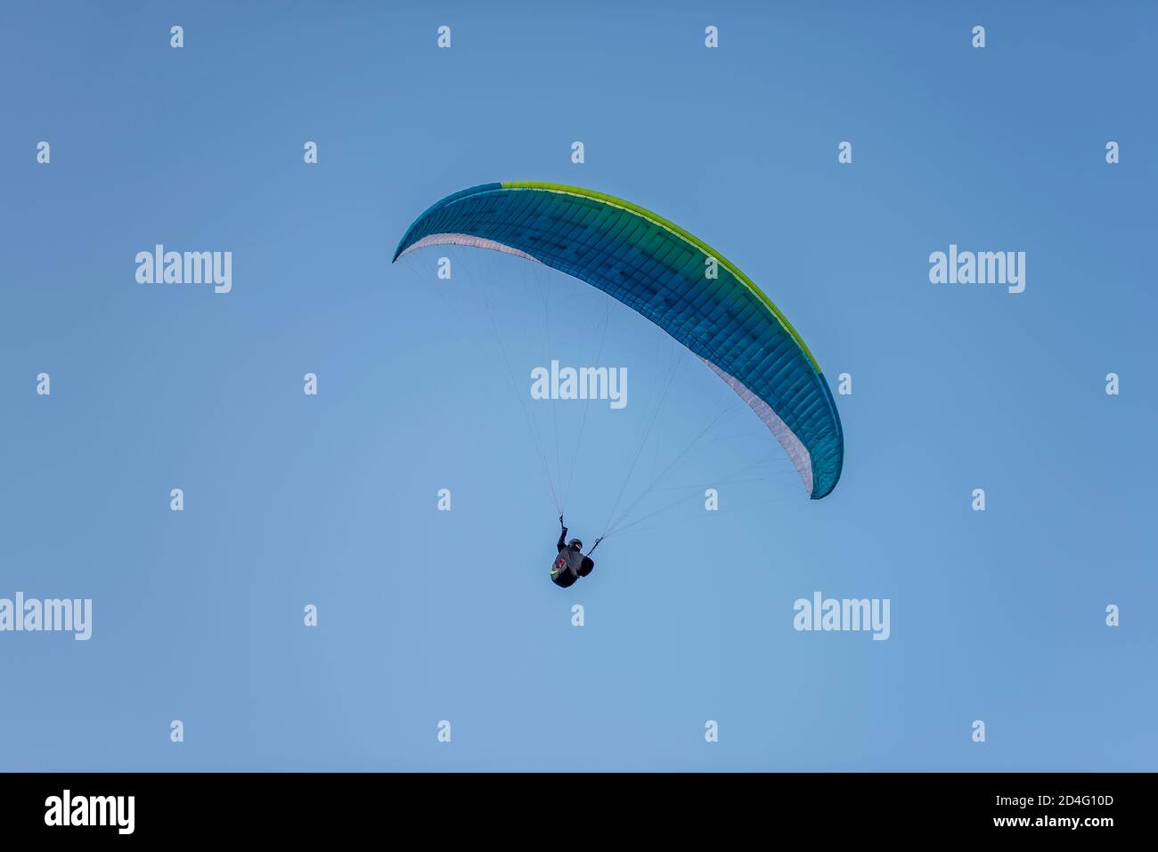 I parapendio con paracadute multicolore volano in alto nel cielo blu limpido sopra ripide scogliere. Paracadutismo, adrenalite, amore per l'altezza, rischio, libertà Foto Stock