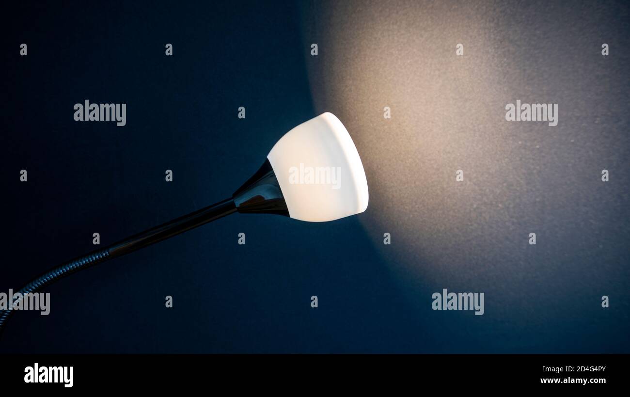 Lampada illuminata parete nera in una stanza, spazio per testo o idee Foto Stock