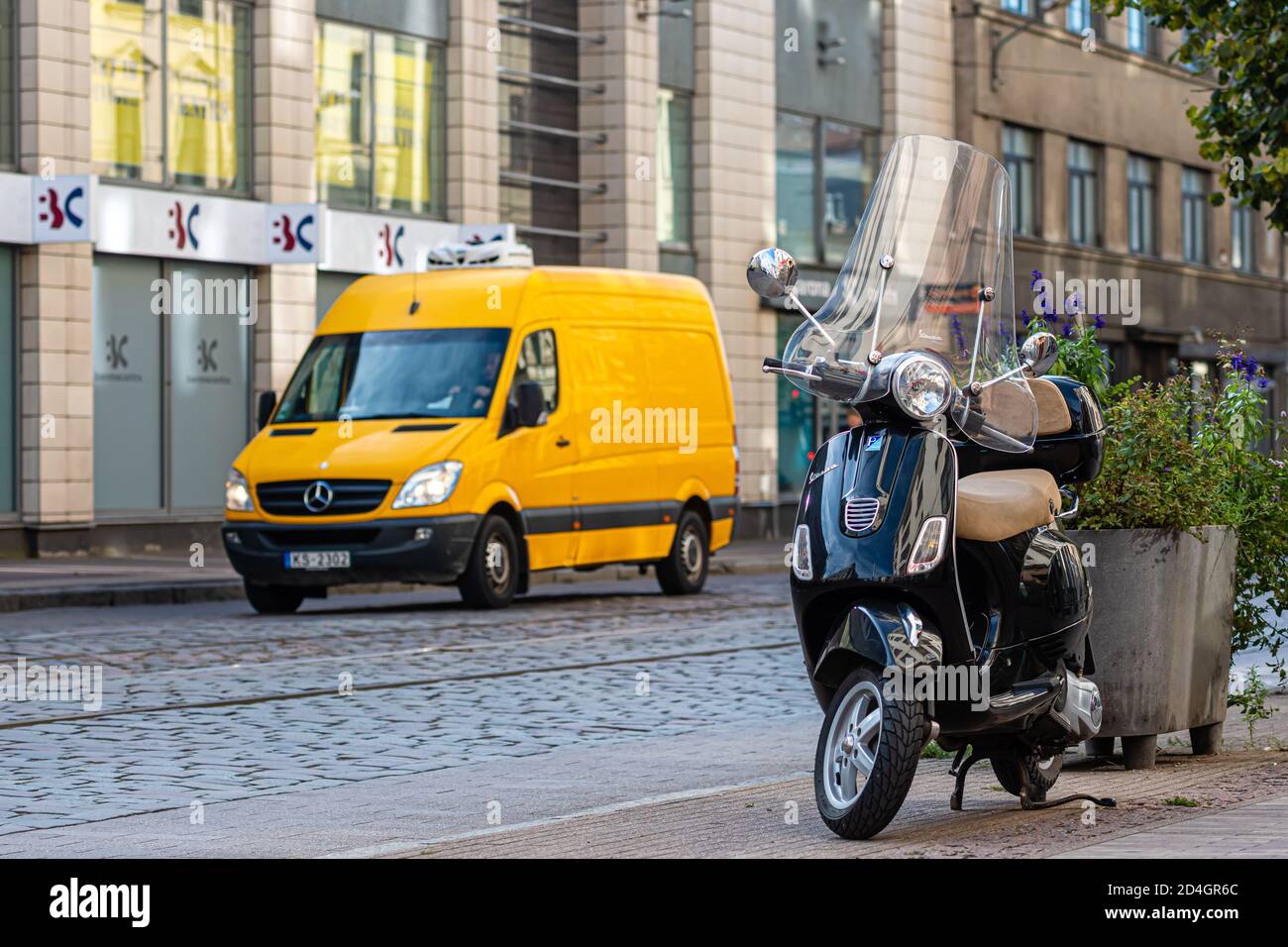 Riga, Lettonia - 8 ottobre 2020: Vespa nero classico parcheggiato su un marciapiede pedonale nella strada del centro città Foto Stock