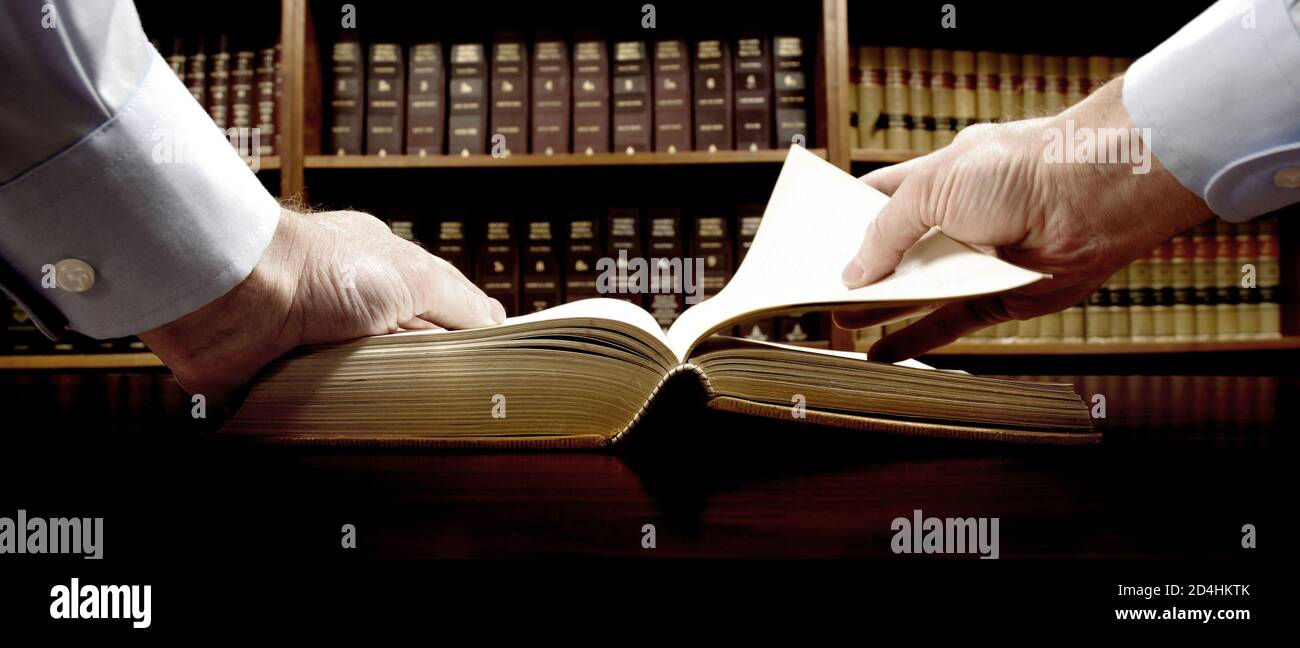 Le mani sono in possesso di un vecchio libro con Libreria in background Foto Stock
