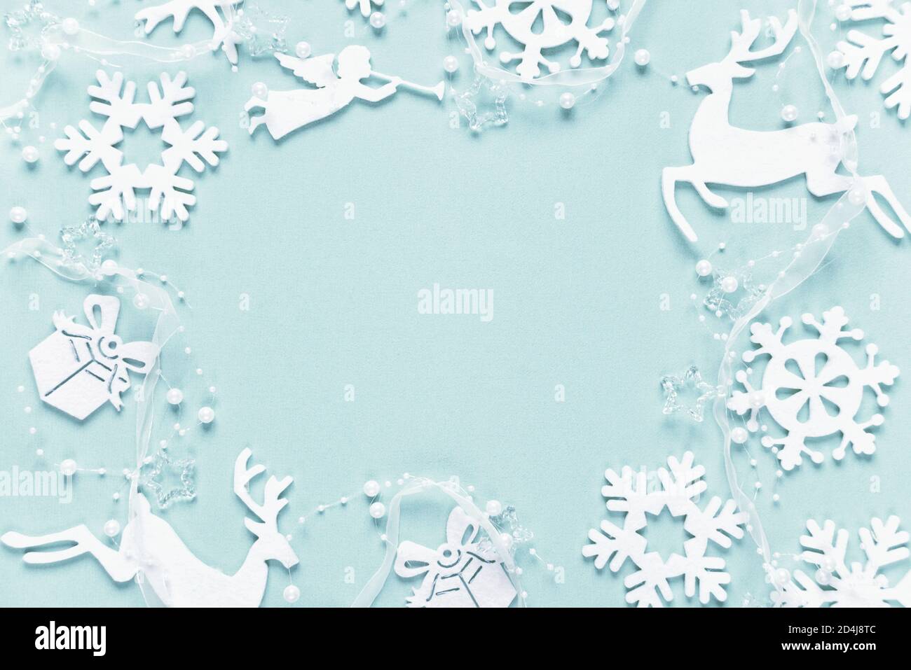 Cornice di Natale composta da bianco decorazione di natale: Fiocchi di neve, cervi, angelo volante e scatole regalo sono su sfondo blu. Composizione piatta per posa per Foto Stock