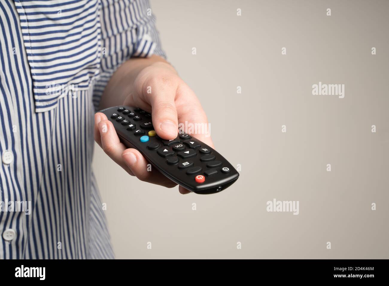 Telecomando nelle mani di una donna su sfondo beige. Foto Stock