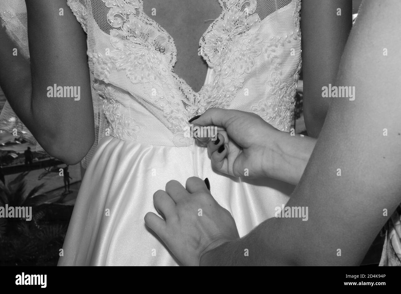 Colpo di primo piano in scala di grigi di una persona che zipa su di una donna abito da sposa Foto Stock