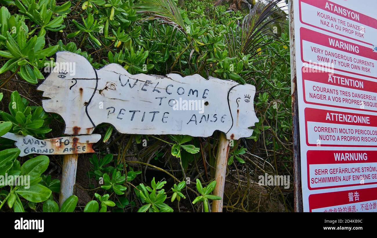 La Digue, Seychelles - 09/30/2018: Cartello di benvenuto della spiaggia Petite Anse oltre ad un altro segno di avvertimento di pericolose correnti in diverse lingue. Foto Stock
