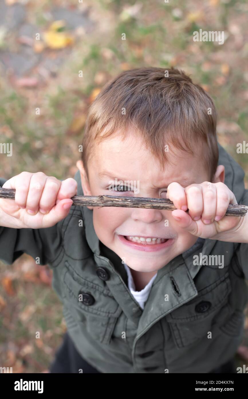 Piccolo ragazzo che gioca con bastone all'aperto in autunno Foto Stock