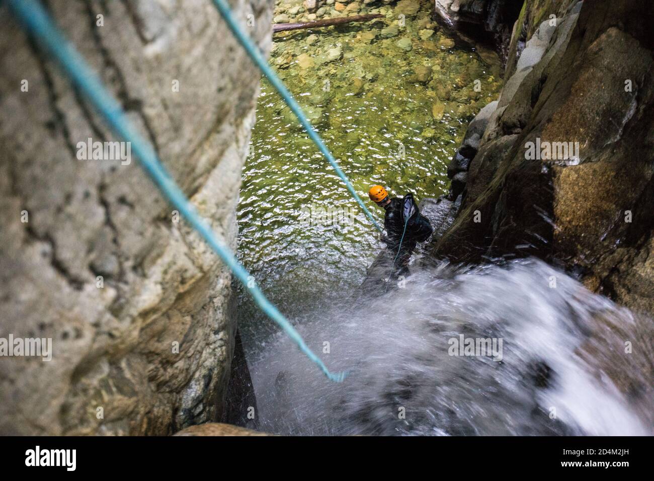 Uomo in piedi sulla sporgenza mentre si abbelliva la cascata nel canyon. Foto Stock