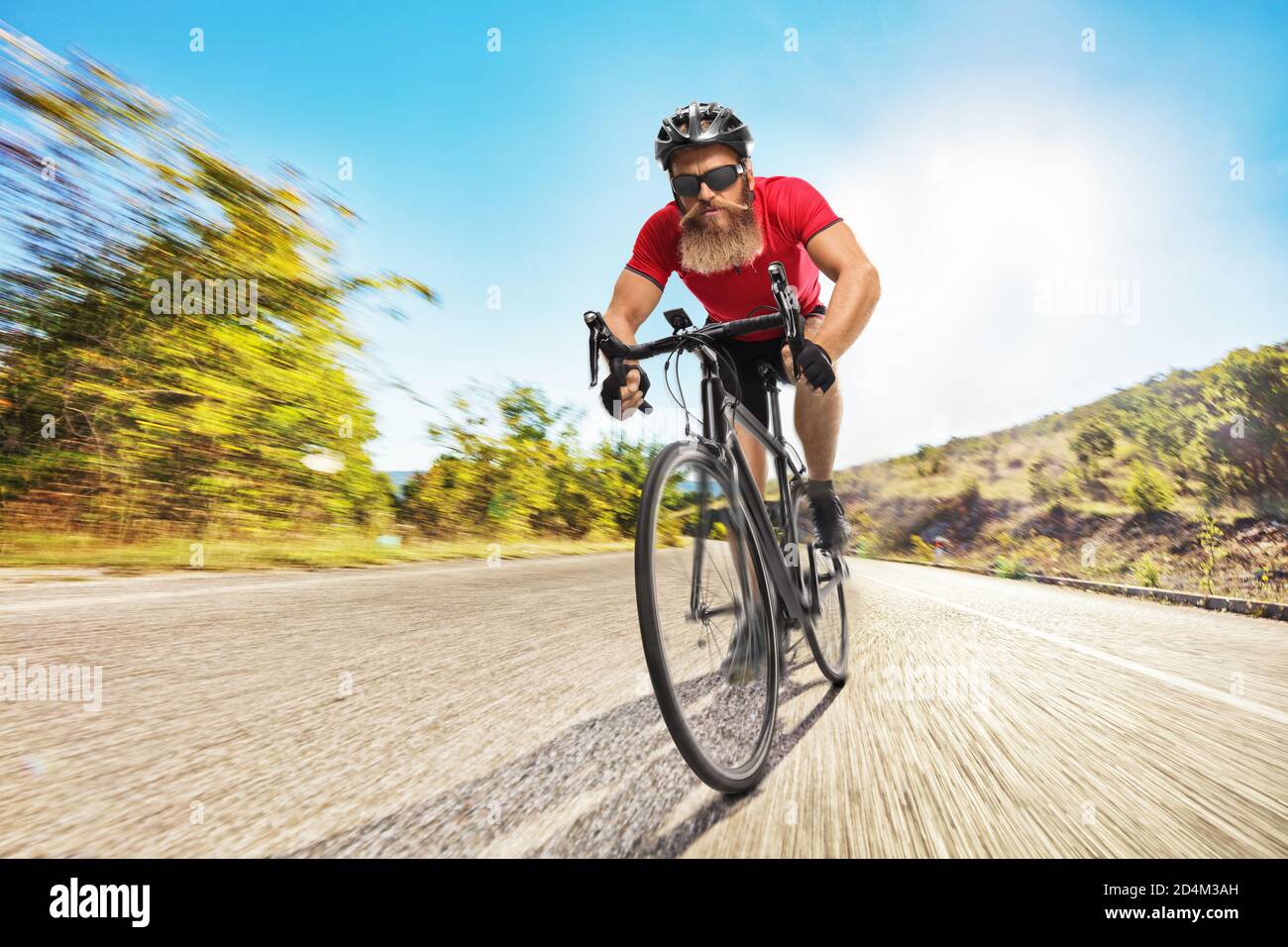 Ciclista con un casco che cavalca una bicicletta su un strada aperta Foto Stock
