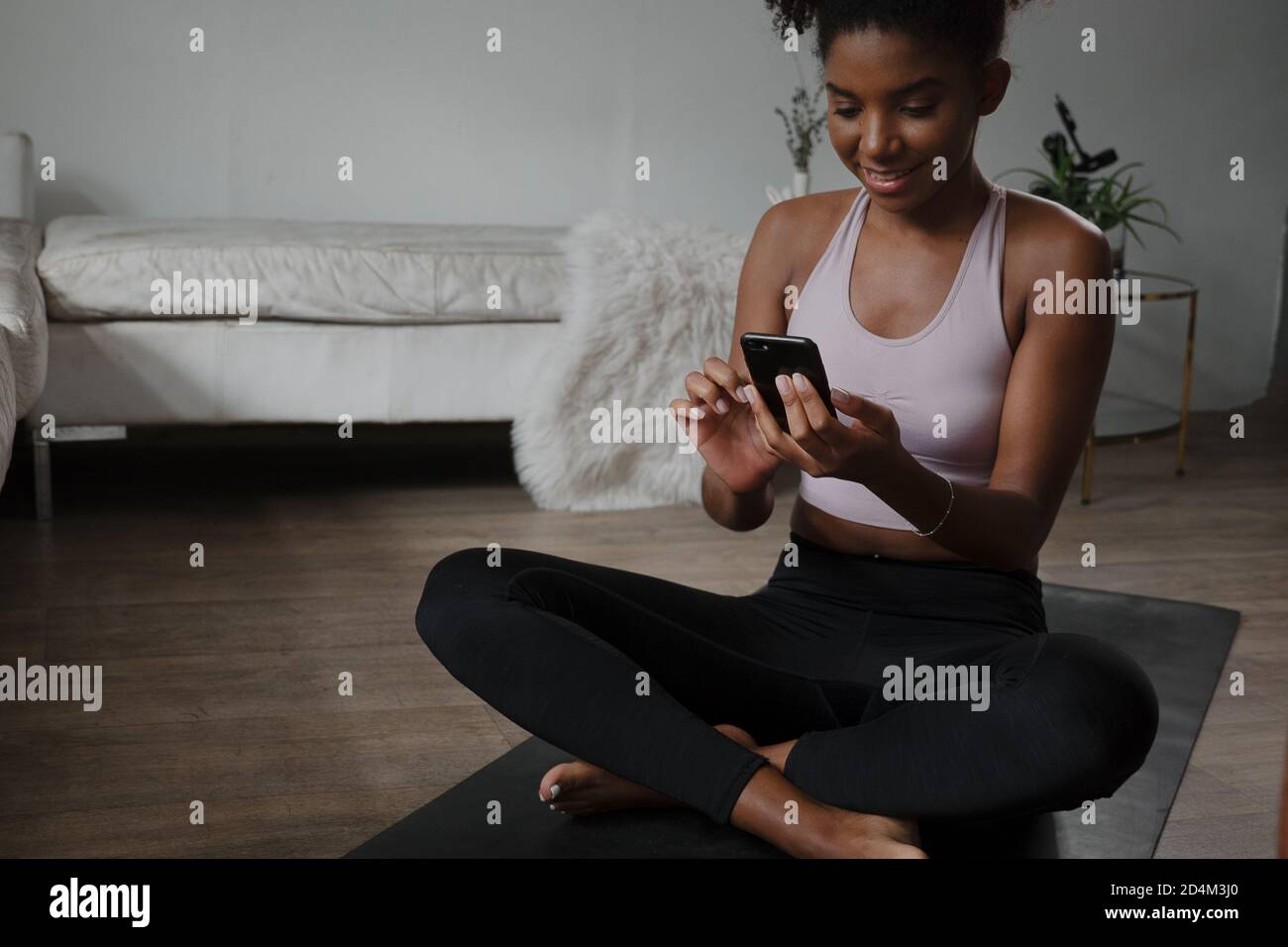 Smartphone per la navigazione di giovani donne multietniche mentre ci si allena a casa Foto Stock