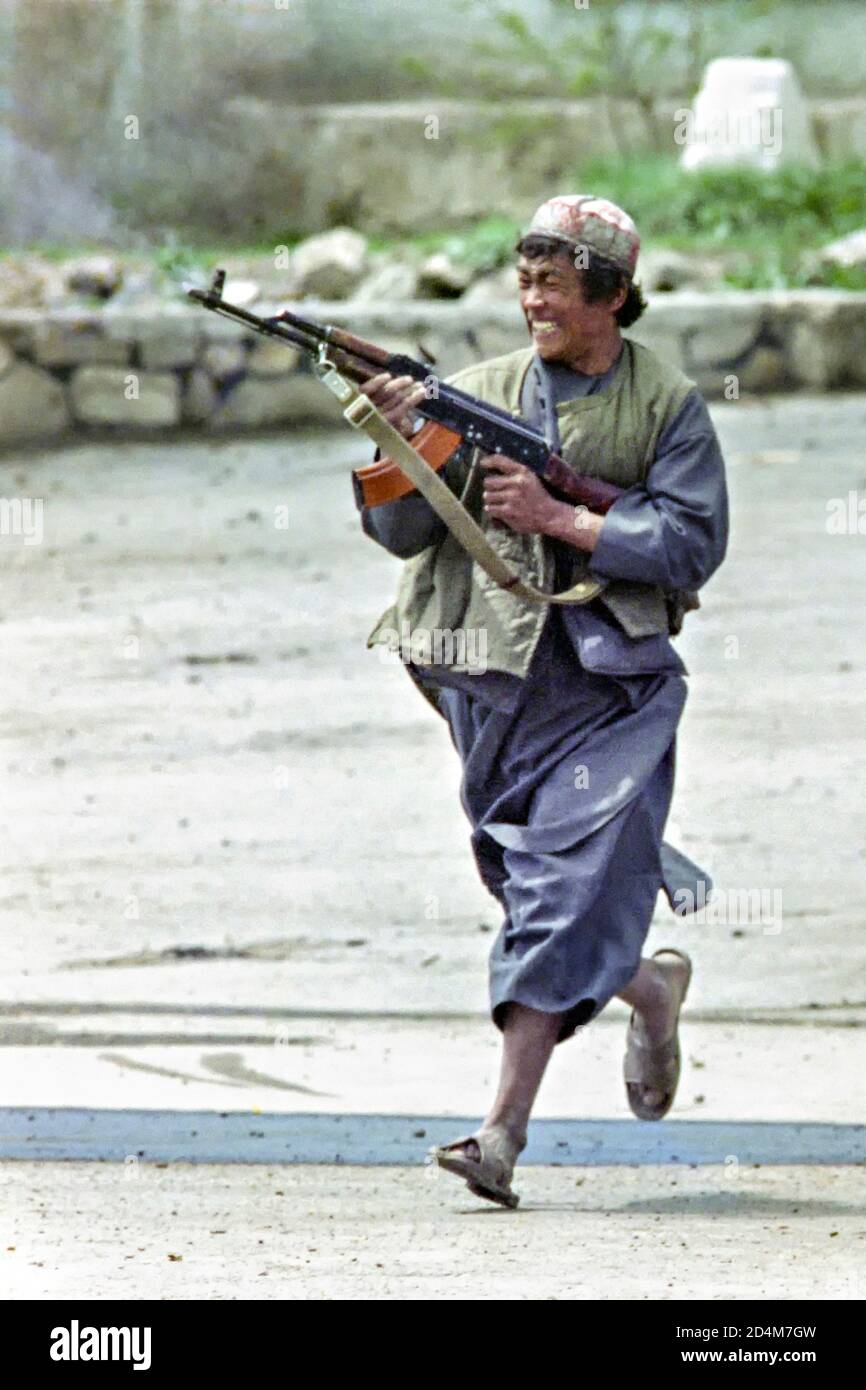 Un combattente guerrigliero tagico afgano con l'Alleanza del Nord spara la sua pistola a macchina AK-47 prodotta dall'Unione Sovietica contro le forze ribelli guidate da Gulbuddin Hekmatyar il 22 aprile 1992 a Kabul, Afghanistan. Dopo la sconfitta del governo comunista, i ribelli afghani iniziarono a lottare per il controllo della capitale. Foto Stock