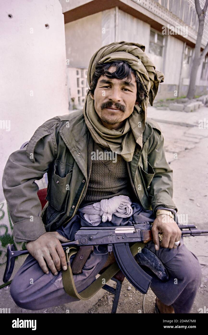 Un combattente guerrigliero tagico afgano con l'Alleanza del Nord detiene la sua pistola a macchina AK-47 fabbricata dall'Unione Sovietica mentre si occupa di un angolo di strada il 22 aprile 1992 a Kabul, Afghanistan. Dopo la sconfitta del governo comunista, i ribelli afghani iniziarono a lottare per il controllo della capitale. Foto Stock