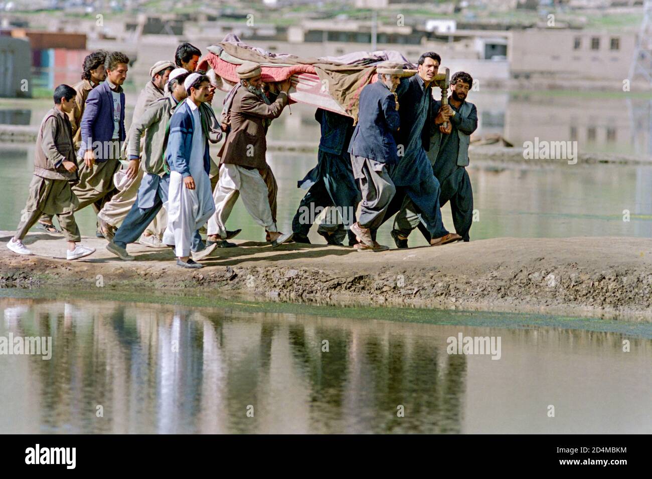 I membri della famiglia trasportano il corpo di un combattente guerriglia dei mujahideen afghani ucciso durante i combattimenti di fazione ai terreni di sepoltura di Martyrs Hill 20 aprile 1992 a Kabul, Afghanistan. Dopo la sconfitta del governo comunista, i ribelli afghani iniziarono a lottare per il controllo della capitale. Foto Stock
