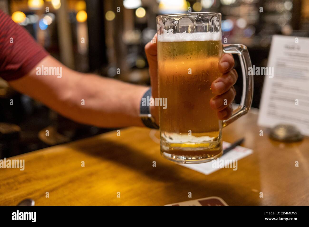 un uomo tiene un grande bicchiere di birra nel suo mano Foto Stock