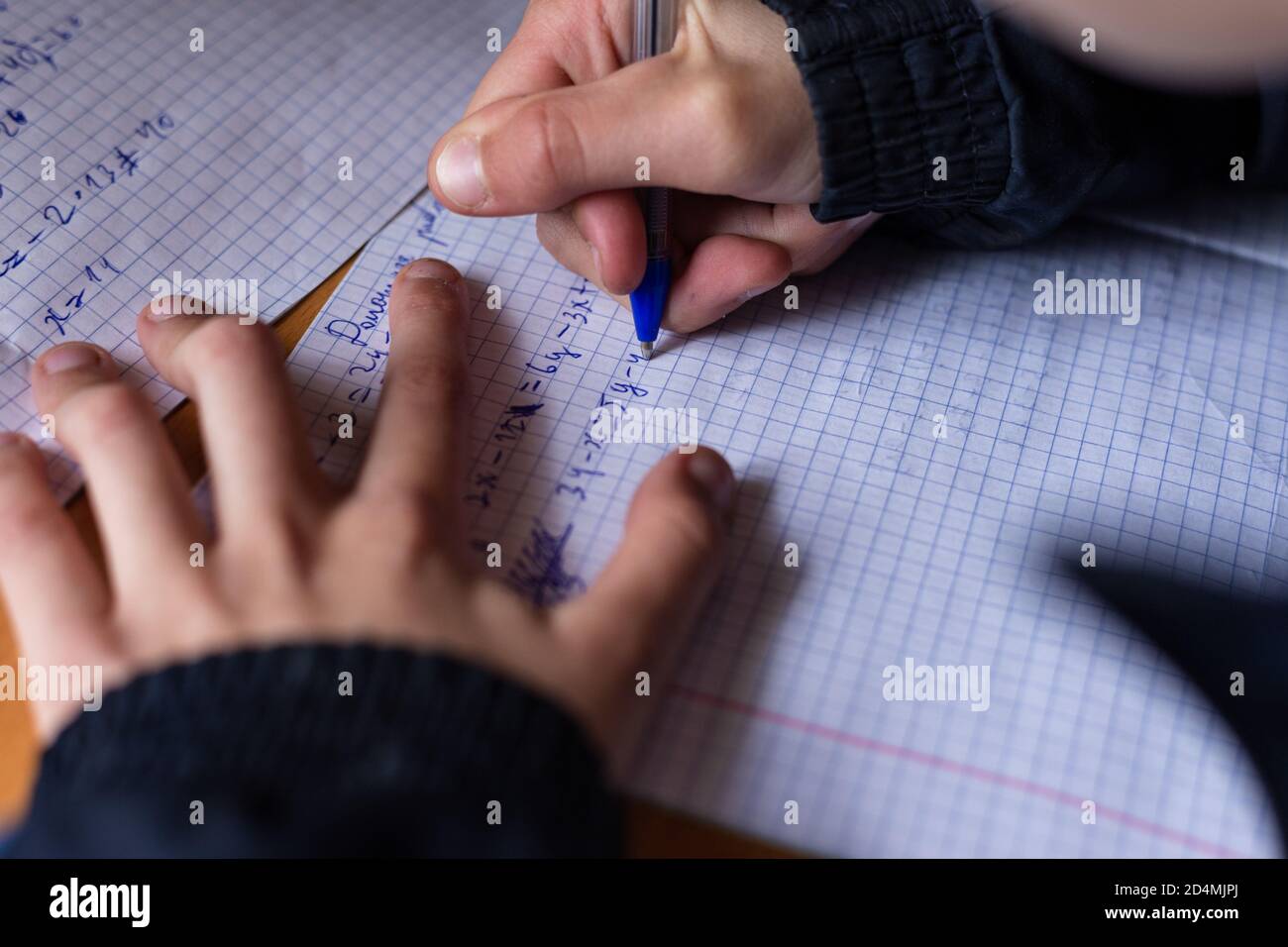 Il ragazzo scrive in un taccuino. Il bambino sta facendo i compiti. Penna e notebook. Foto Stock