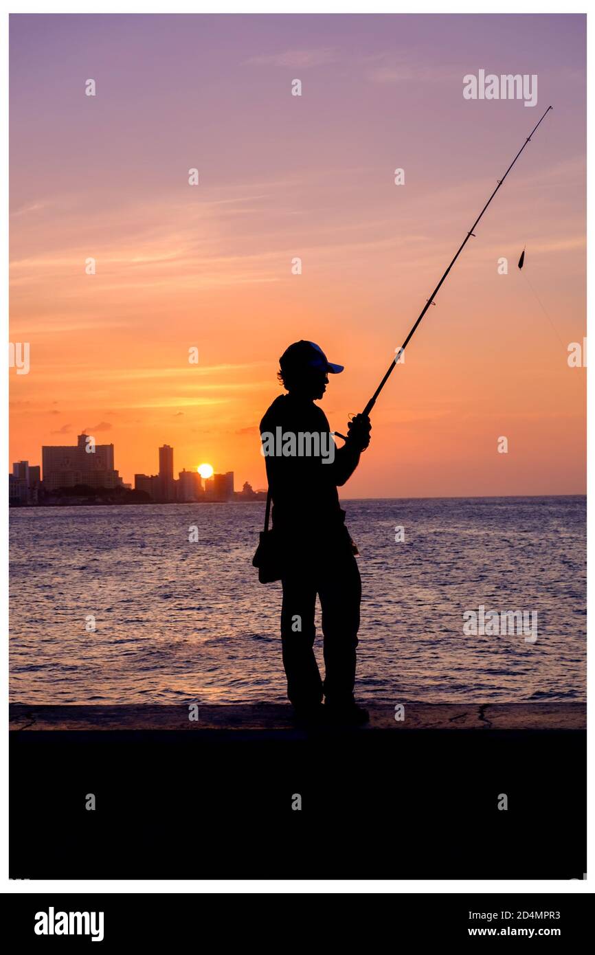 Bellissimo tramonto a l'Avana con la silhouette di un pescatore Sulla parete di mare di Malecon Foto Stock