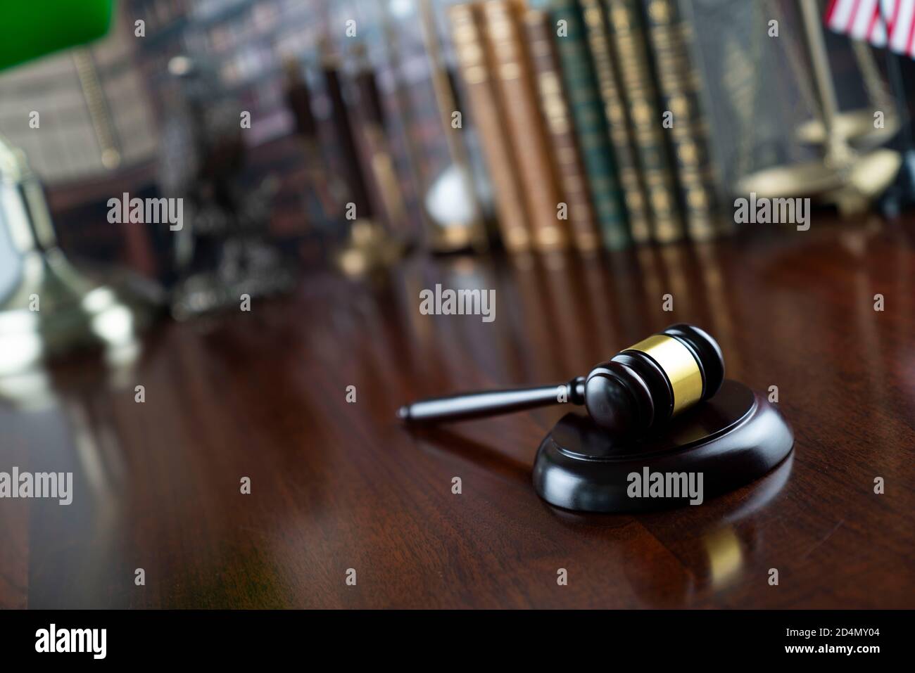 Giudice ufficio. Gavel su tavola bruna brillante e raccolta di libri legali nella libreria. Foto Stock