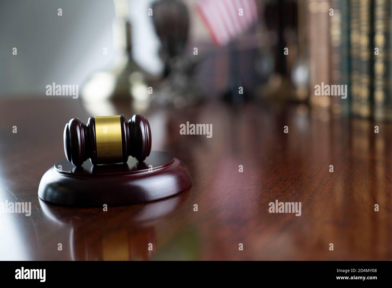 Giudice ufficio. Gavel su tavola bruna brillante e raccolta di libri legali nella libreria. Foto Stock