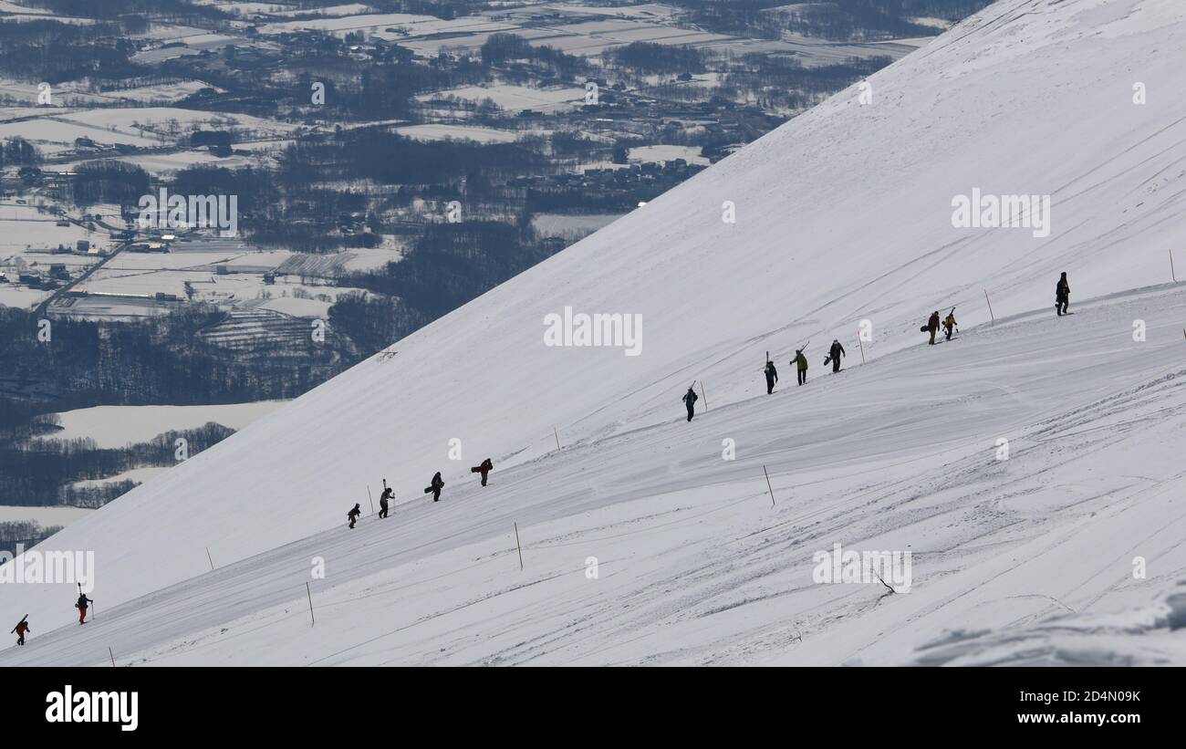 Una fila di snowboarder escursione fino alla cima di a. montagna Foto Stock