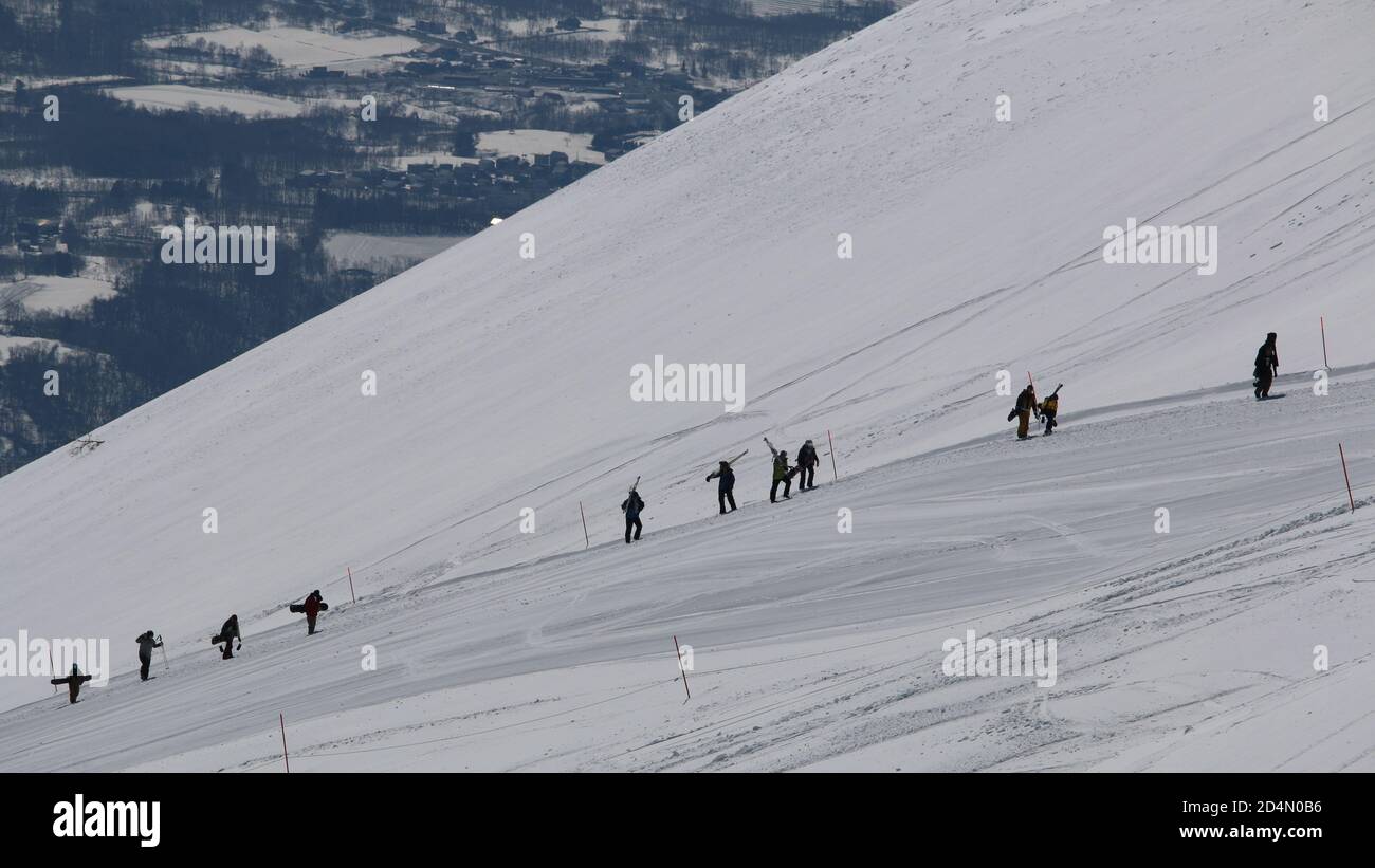Una fila di snowboarder si dirige verso la cima di una montagna, Niseko, Hokkaido, Giappone Foto Stock