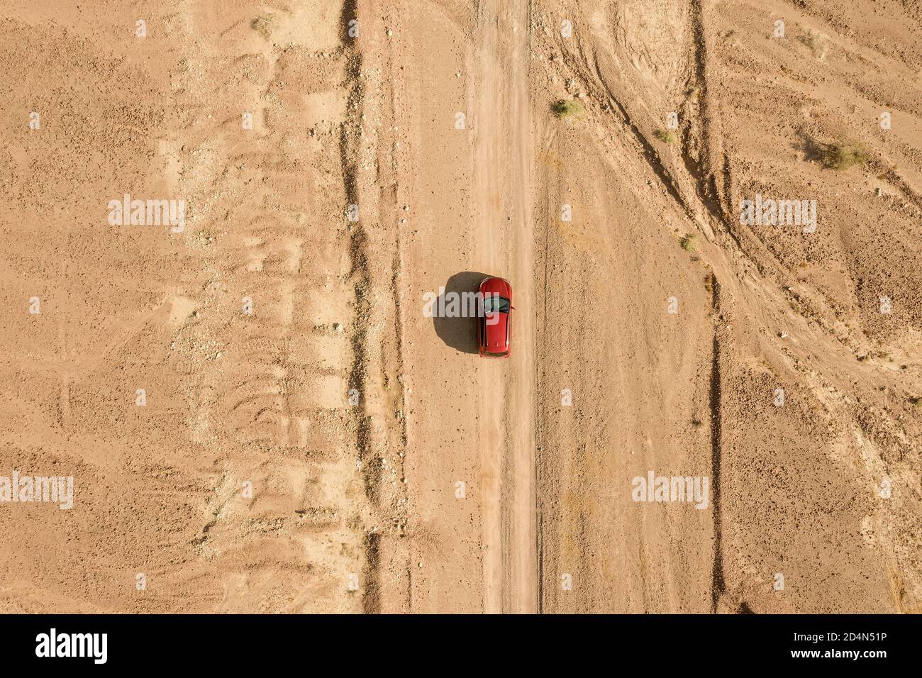 SUV rosso su un percorso desertico, immagine aerea ad alta quota. Foto Stock