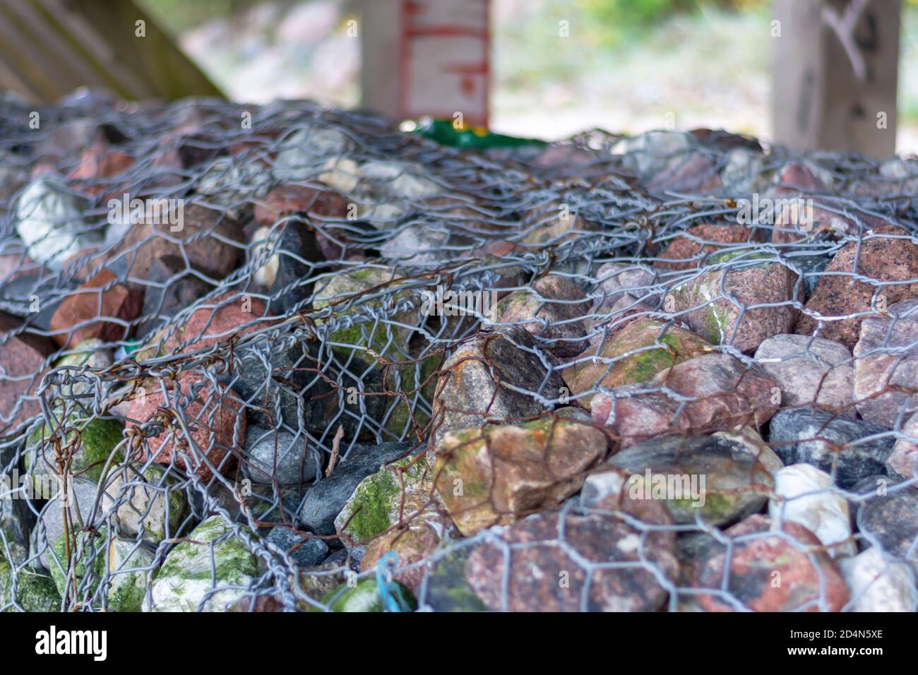 Pietre naturali fissate con una rete metallica per rinforzare la costa. Primo piano, messa a fuoco selettiva. Foto Stock