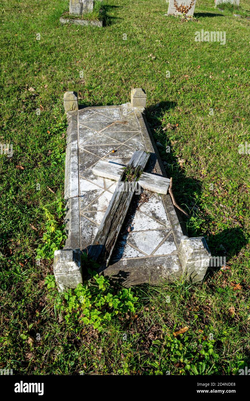 Croce di legno marcio sulla tomba in St Mary il cimitero della chiesa della Vergine in Hawkwell, Rochford, vicino Southend, Essex, Regno Unito. Decadimento, croce rotta Foto Stock