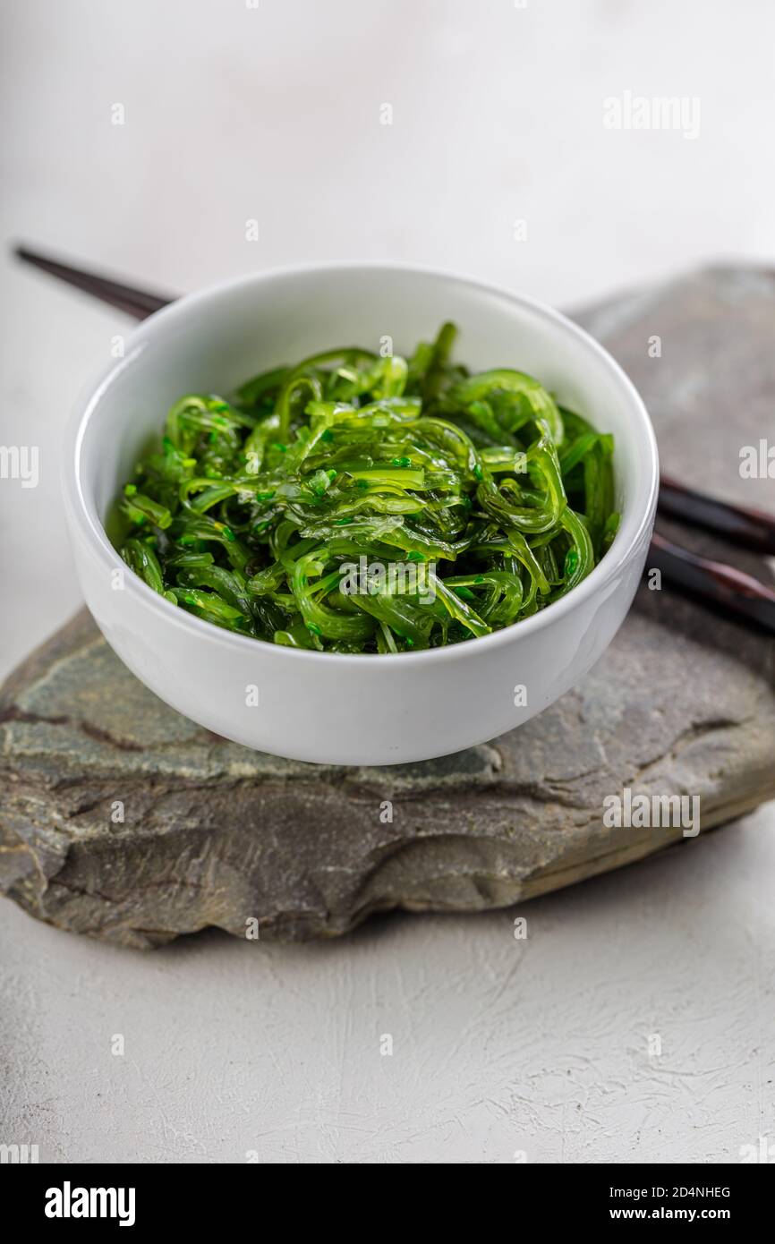 Foto ritagliata di insalata verde di alghe di wakame con bastone il ristorante Foto Stock