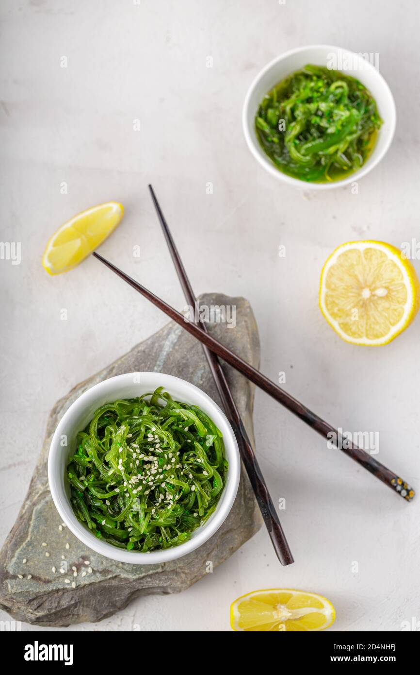 Foto ritagliata di insalata verde di alghe di wakame con bastoncino e. limone al ristorante Foto Stock
