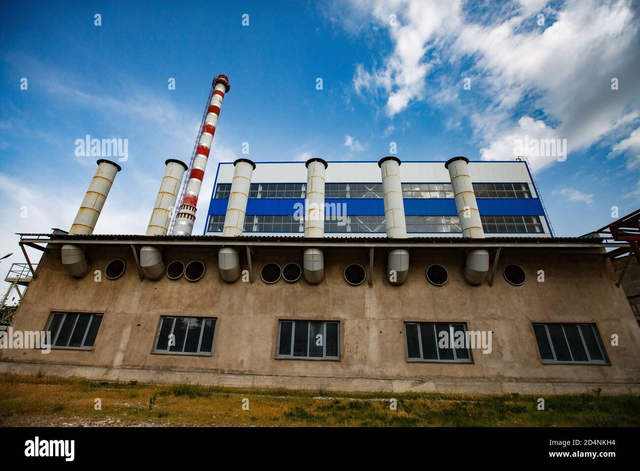 Fabbrica di vetro Darkhan. Centrale elettrica a gas, camino a strisce rosso e bianco e edificio industriale in primo piano. Vista grandangolare. Cielo blu con Clo Foto Stock