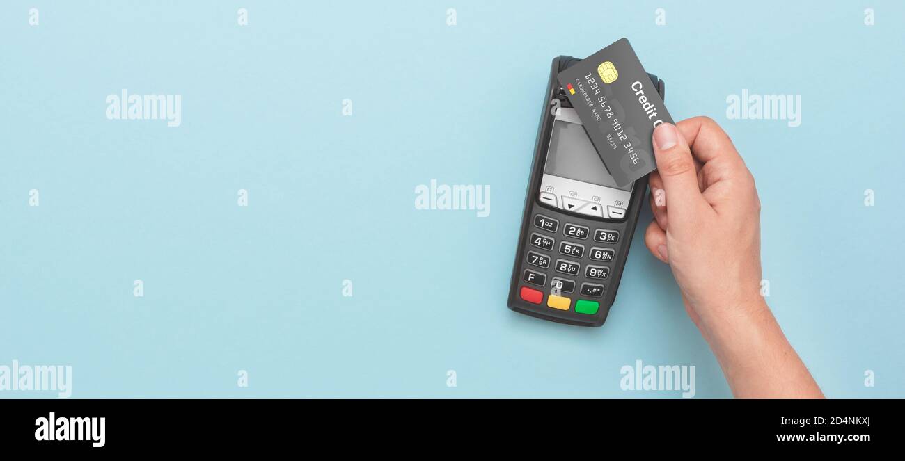 Terminale di pagamento con carta di credito. Uomo con carta di credito. Immagine ampia con spazio di copia e sfondo blu Foto Stock