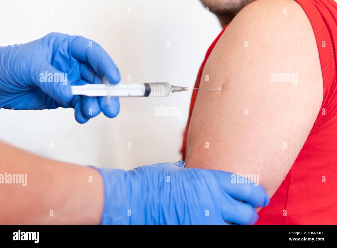 Primo piano del medico che effettua la vaccinazione al paziente su sfondo bianco, concetto sano. Prevenzione della diffusione del coronavirus 19 Foto Stock