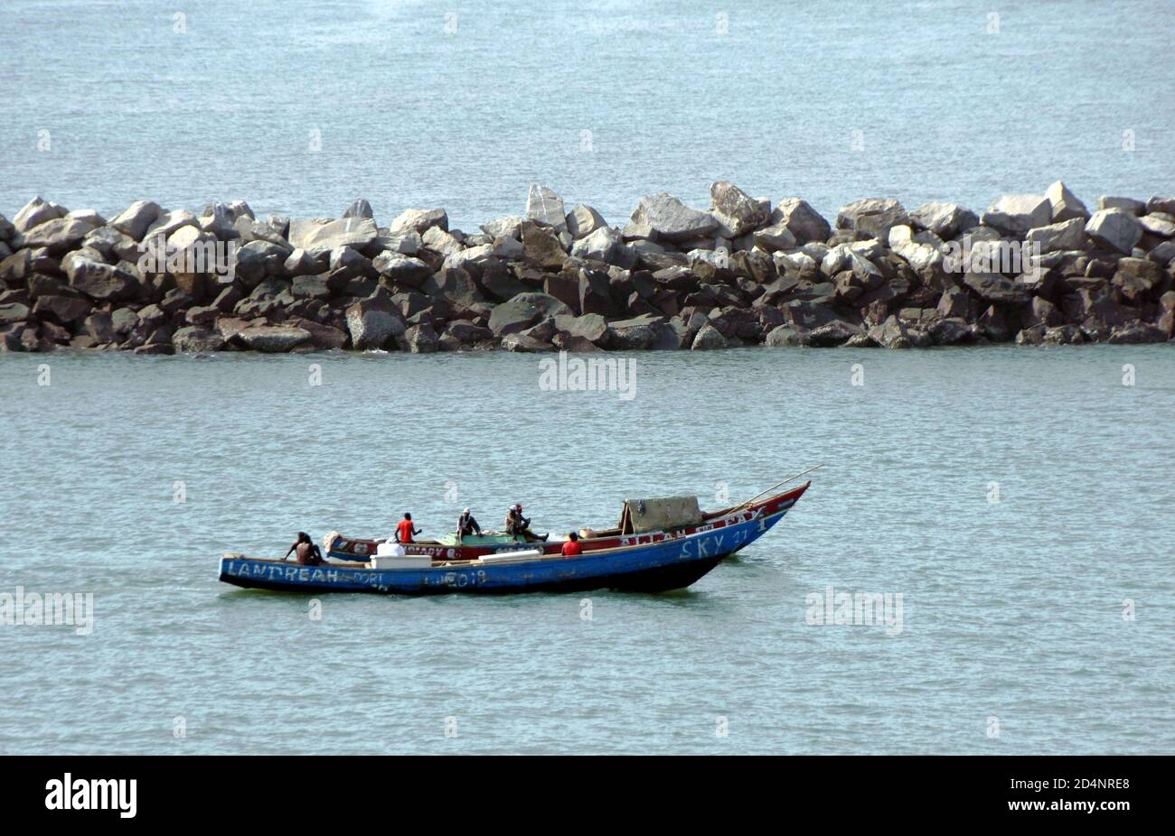 Vecchie barche da pesca in legno blu con gente del posto che si dirigono verso il terreno di pesca vicino al porto di Conakry in Guinea. Foto Stock