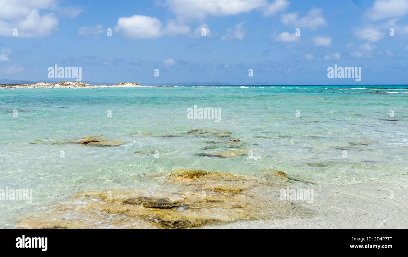 Vista di una spiaggia mediterranea sulla superficie dell'acqua, sabbia bianca cristallina e cielo blu sullo sfondo, isola di Formentera, Isole Baleari Foto Stock