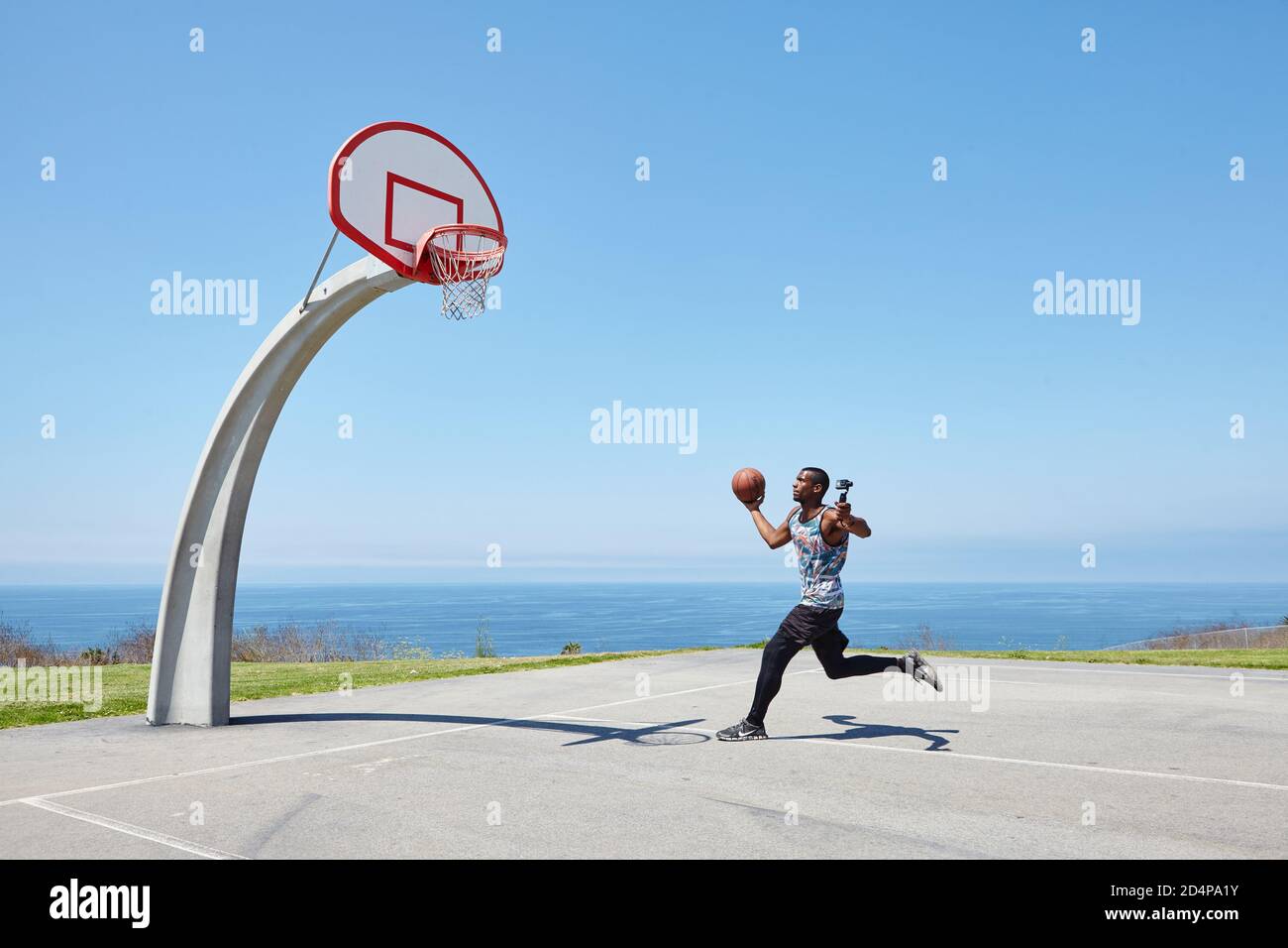 Basketball Player che corre in riva al mare con selfie camera Foto Stock