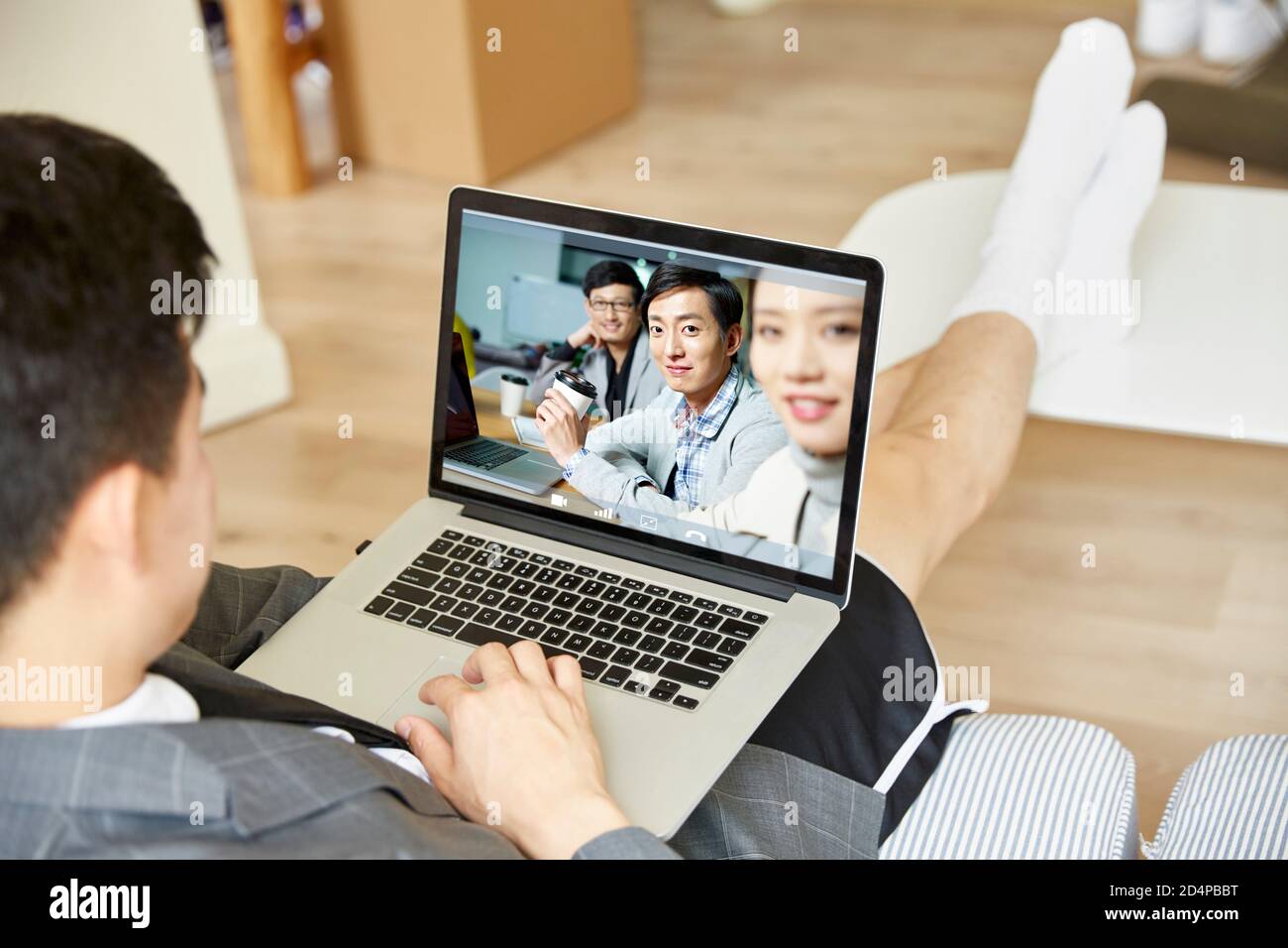 giovane uomo asiatico che lavora da casa incontro online con un team di persone aziendali tramite videoconferenza utilizzando un computer portatile Foto Stock