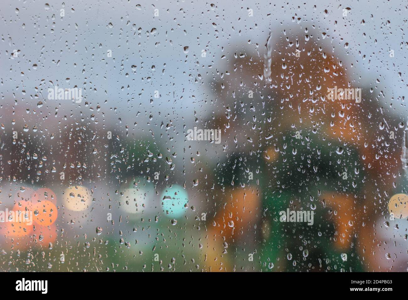 Gocce su vetro in giorno piovoso. Pioggia fuori finestra in città. Consistenza di gocce di pioggia, vetro bagnato. Finestra piovosa background.City semafori Foto Stock