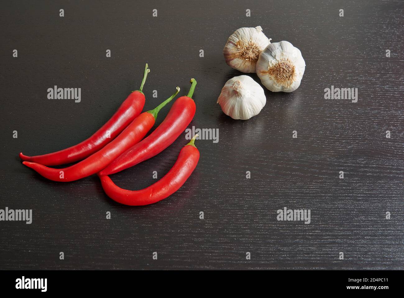 Peperoncino rosso e aglio crudo su tavolo nero testurizzato Foto Stock