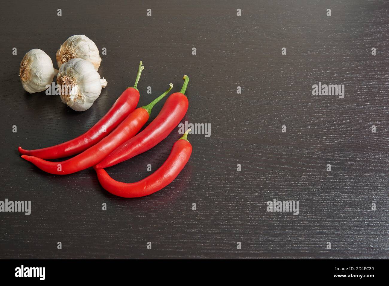 Peperoncino rosso e aglio crudo su tavolo nero testurizzato Foto Stock