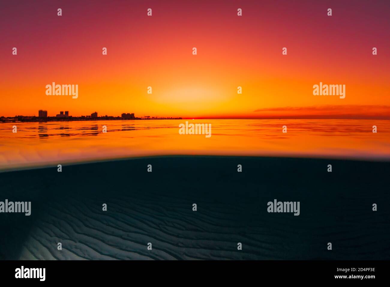 Vista divisa con tramonto luminoso e fondale marino sabbioso sottomarino. Foto Stock