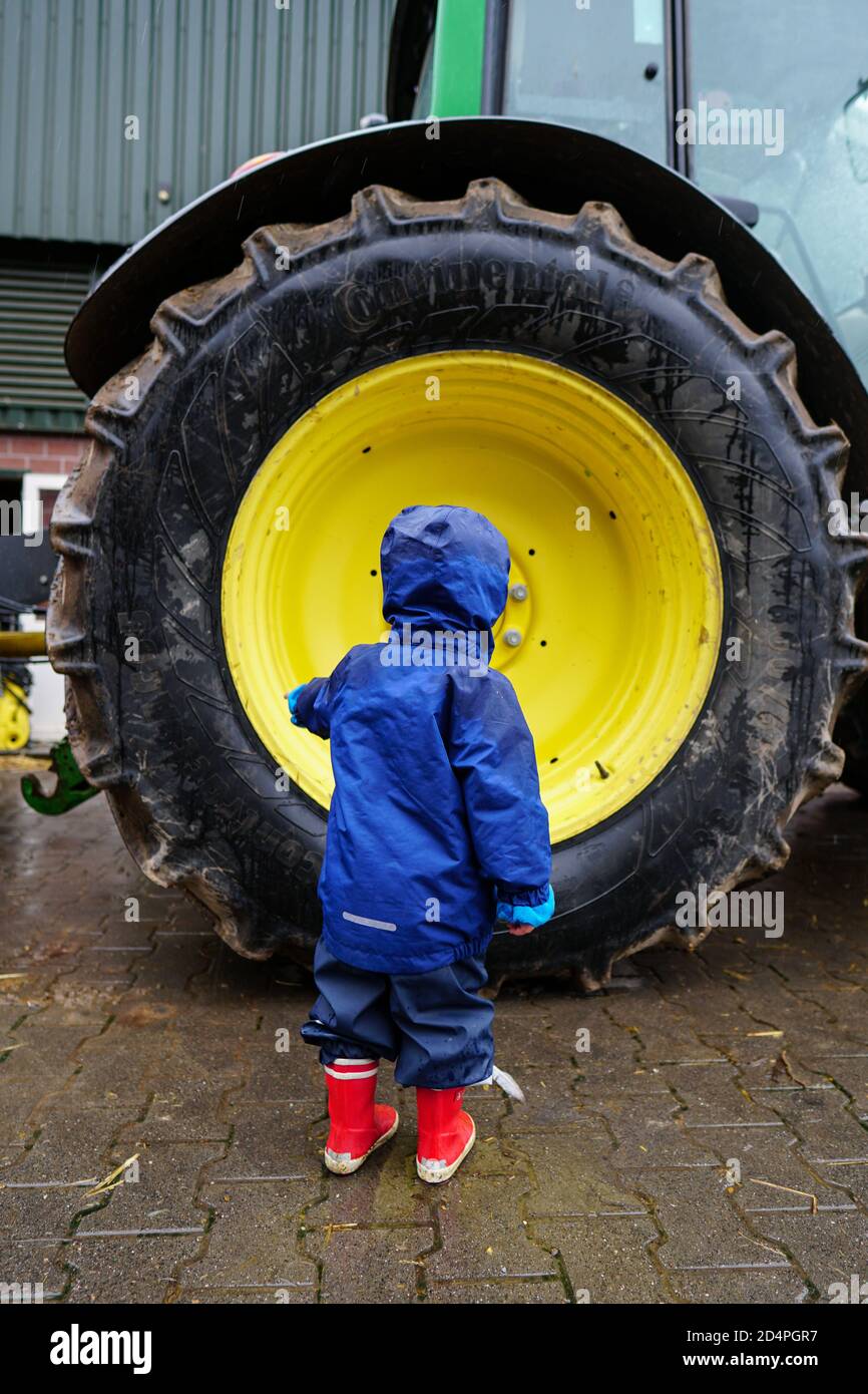 Immagine verticale di un bambino in piedi vicino a un camion di grandi dimensioni pneumatico Foto Stock