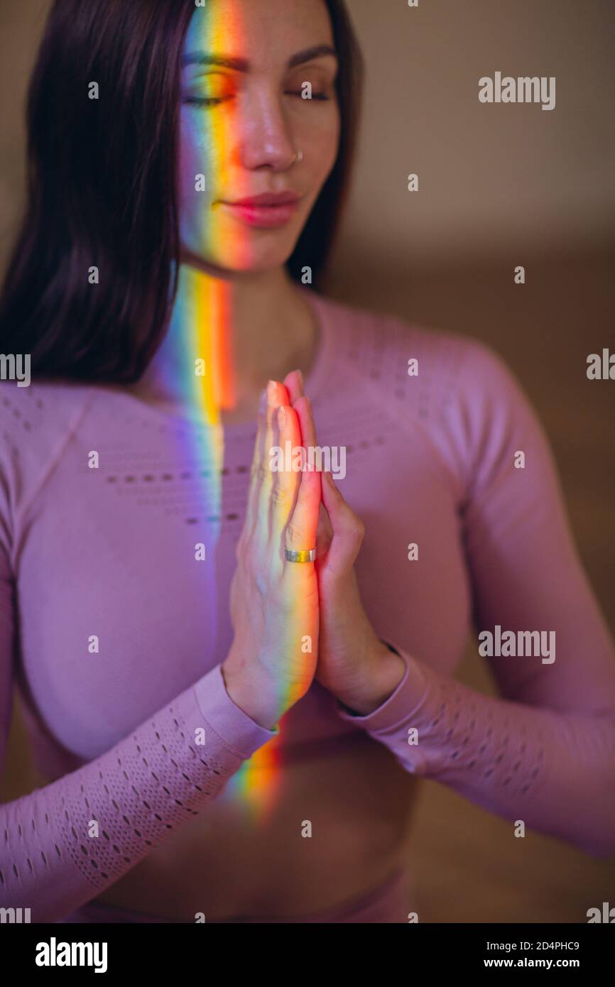 Ritratto della donna che pratica meditazione e yoga con luce arcobaleno accesa il suo corpo e il suo volto Foto Stock