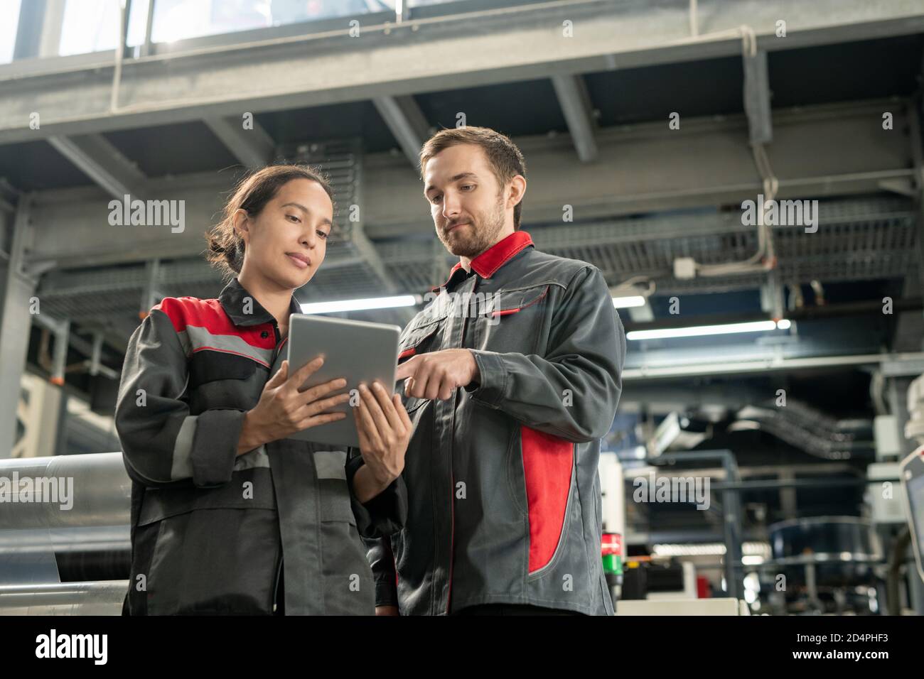 Due giovani responsabili del controllo di qualità della fabbrica di lavorazione dei polimeri che utilizza tablet Foto Stock
