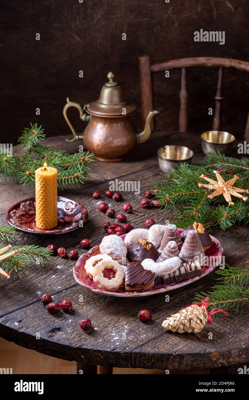 Biscotti di Natale tradizionali su un tavolo, con i fianchi di rose secche, rami di abete rosso e ornamenti di paglia Foto Stock